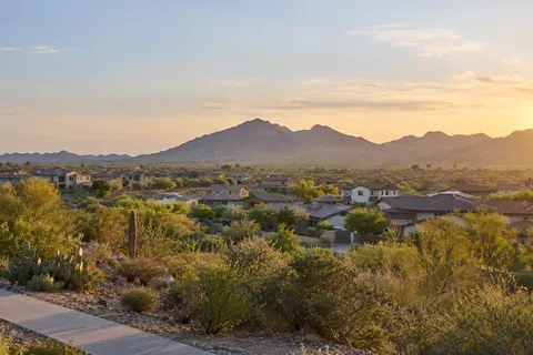 Illustrative broad Phoenix Valley neighborhood and foothill panorama in warm evening light. Not a depiction of Madera or an available home.