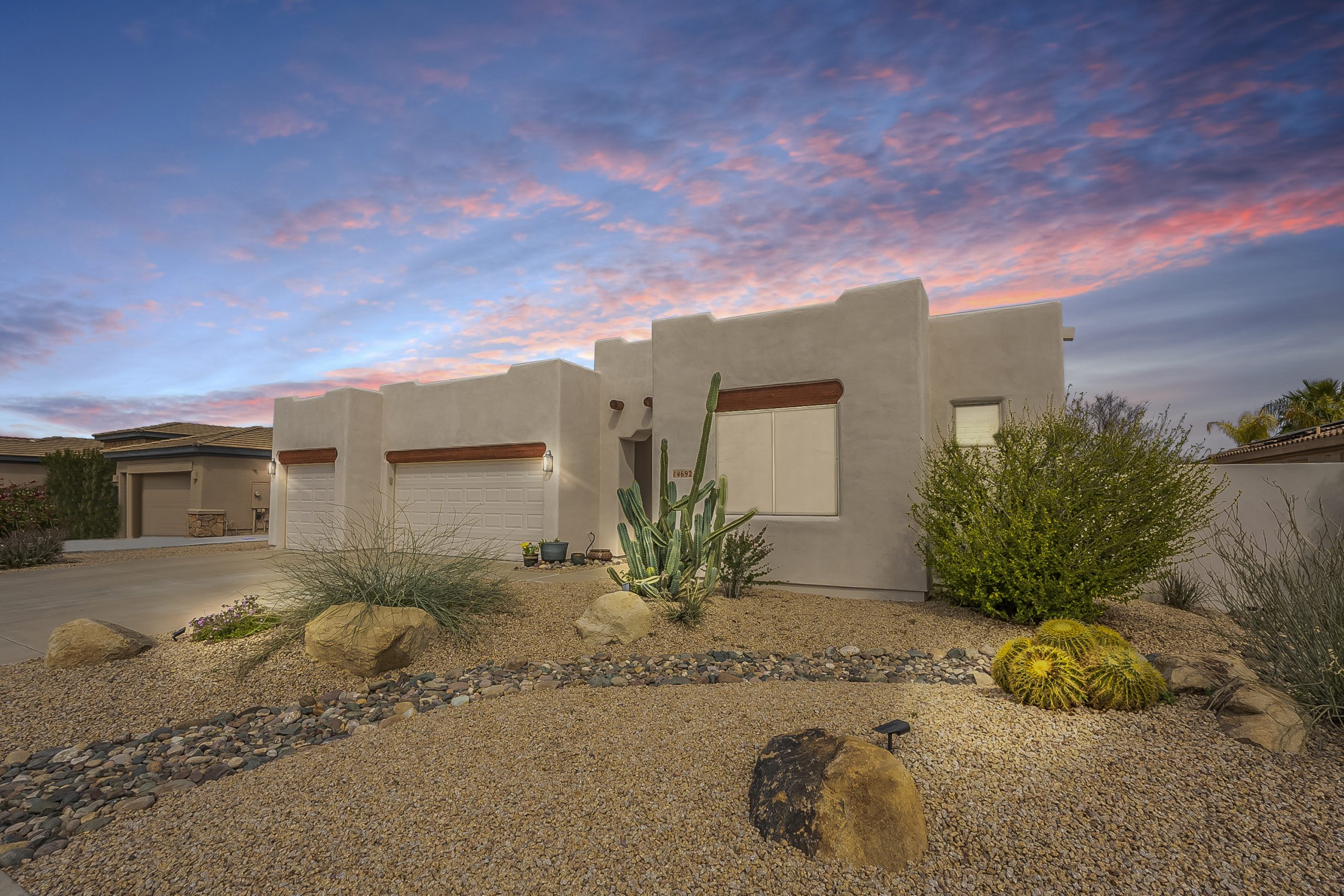 real estate listing photo showing the front of an adobe style home in goodyear, az with a 3 car garage