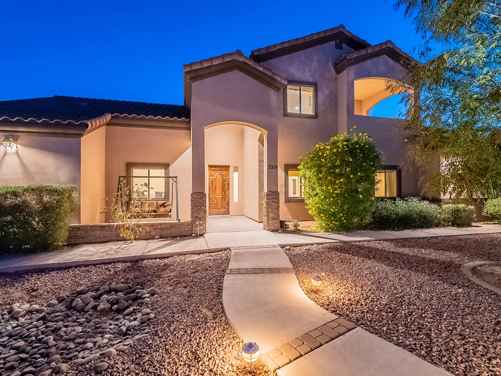 Litchfield Park Arizona home with an illuminated arched entry at dusk