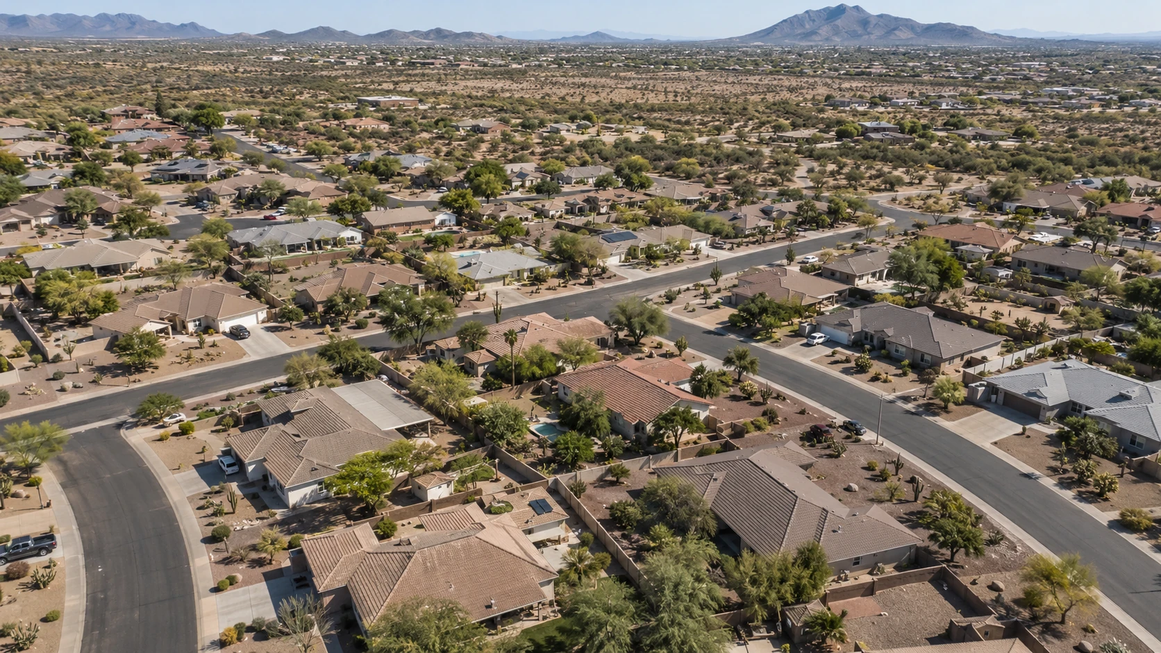 Conceptual aerial view of a desert suburban neighborhood with tile-roof homes and distant mountains